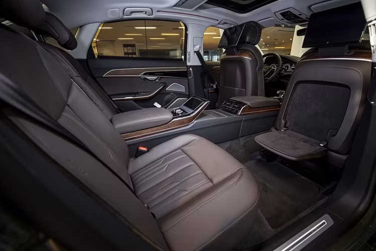 Điểm nhấn của Audi A8L 2022 nằm ở hàng ghế sau. Phiên bản cao cấp nhất Premium có phần ốp trung tâm nối dài biến chiếc xe từ 5 chỗ thành 4 chỗ. Phiên bản Plus cũng có những trang bị đáng chú ý như bàn gấp ở lưng ghế phía trước, đèn đọc sách LED ma trận... Toàn bộ ghế ngồi đều được bọc da Valcona.