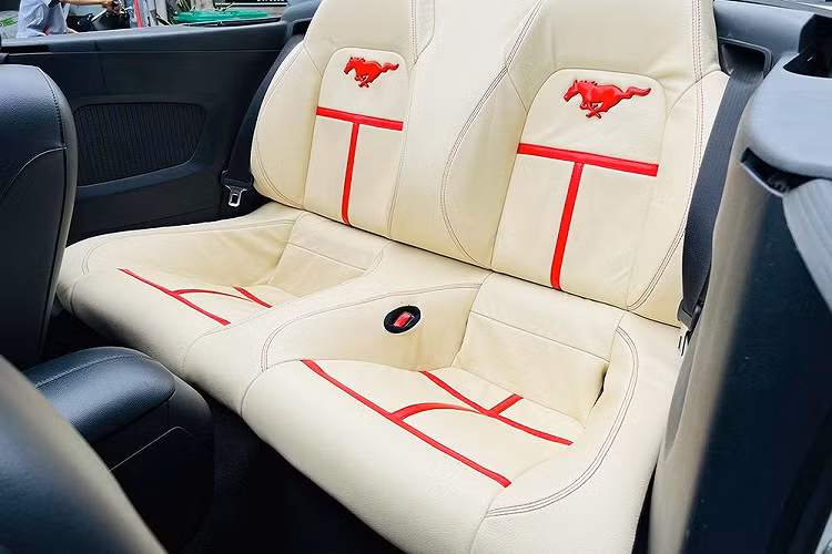 Ngoài ngoại hình được lột xác qua body kit độ và cửa cắt kéo, nội thất chiếc xe Ford Mustang Convertible này còn được bọc da màu kem và thêu thêm logo ngựa hoang trên mặt lưng ghế ngồi màu đỏ để tạo điểm nhấn cho bên trong khoang lái xe. Được biết, số lượng xe Ford Mustang mui trần tại Việt Nam không nhiều và độ cửa cắt kéo chỉ đếm trên đầu ngón tay.