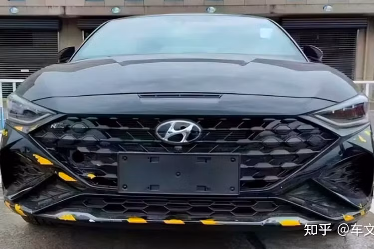 Ở phiên bản N Line mới, mẫu xe sedan Hyundai Lafesta 2023 được trang bị hốc gió trung tâm tích hợp cánh lướt gió nổi bật bên dưới. Khe gió nằm ở hai bên góc cản trước của phiên bản N Line cũng có kích thước lớn hơn. Ngoài ra, lưới tản nhiệt của Hyundai Lafesta N Line 2023 còn được bao quanh bằng viền màu đen thay vì mạ crôm như bản thường và đi kèm logo "N Line" nằm trên góc bên phải.