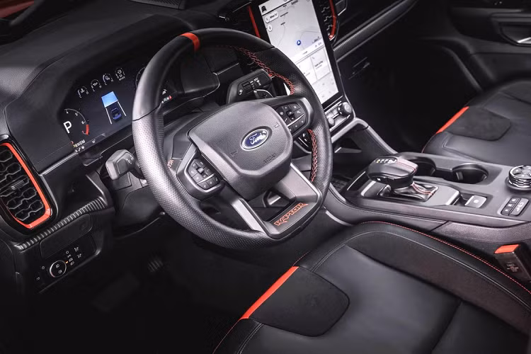 Bước vào bên trong Ford Ranger Raptor 2022, người lái sẽ tiếp tục thấy những thay đổi so với Ranger thông thường. Cụ thể, mẫu xe bán tải hiệu suất cao này được trang bị ghế thể thao, lấy cảm hứng từ máy bay chiến đấu, chỉ khâu màu đỏ, vô lăng bọc da cao cấp, có tính năng sưởi và tích hợp lẫy chuyển số cũng như hệ thống đèn viền.