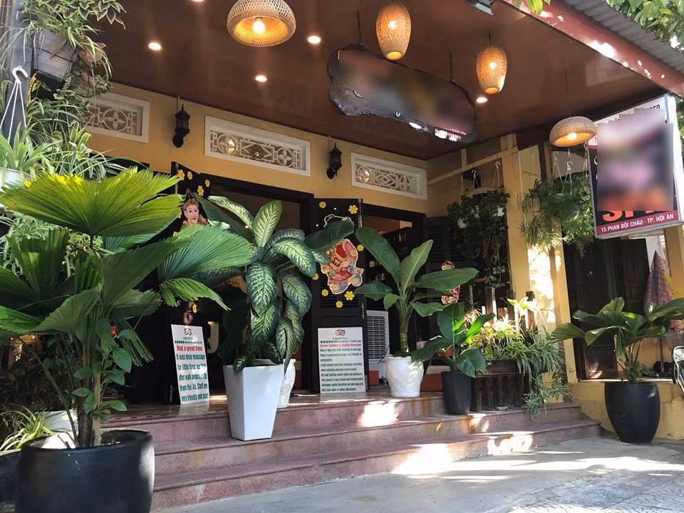 Nhà được sơn vàng bên ngoài, cửa đều bằng gỗ, treo đèn, lát gạch men nhỏ kiểu xưa rất mộc mạc. Ảnh: Zing.