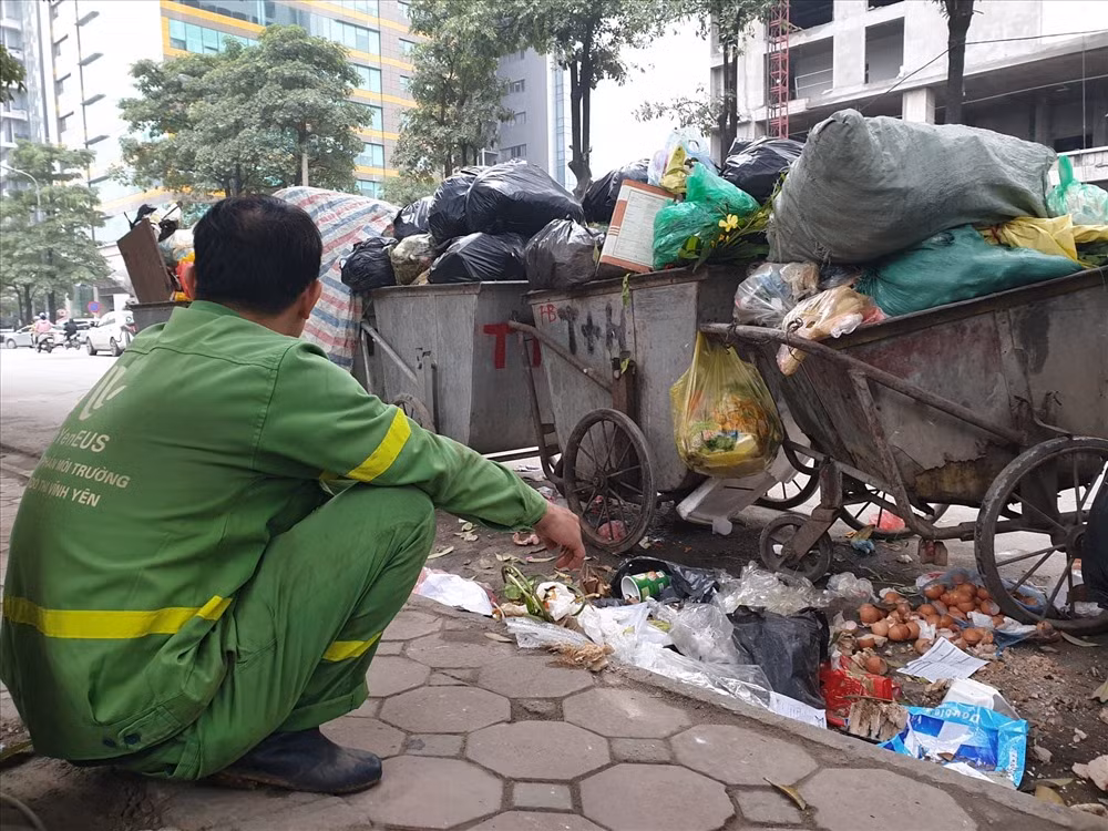 Trao đổi với phóng viên, một công nhân vệ sinh môi trường cho biết, nay là ngày thứ 3 bãi rác Nam Sơn bị chặn nên lượng rác bị tồn đọng rất lớn. Mỗi điểm tập kết có khoảng 2 công nhân phải làm việc liên tục thì mới đạp ứng được số lượng công việc. Bên cạnh đó, việc chờ xe rác đến và chuyển rác lên xe cũng mất rất nhiều thời gian.