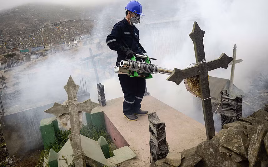 Một công nhân đang khử trùng ở nghĩa trang Nueva Esperanza, vùng ngoại ô Lima, để ngăn chặn virus Zika.