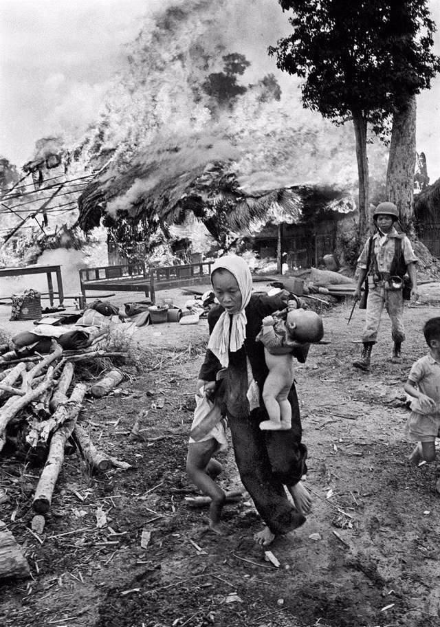 Người mẹ ôm con nhỏ vội vã bỏ chạy khi ngôi nhà bị thiêu rụi. Ảnh chụp tháng 7/1963.