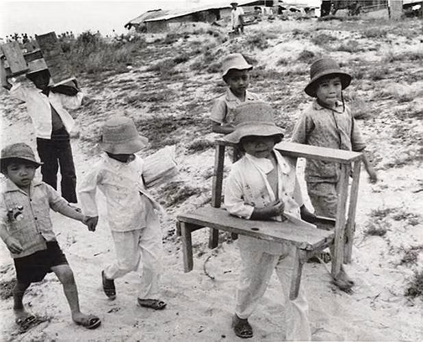 Một số học sinh mang sách vở, bàn ghế đến lớp học ngoài trời ở Quảng Trị ngày 24/9/1973.