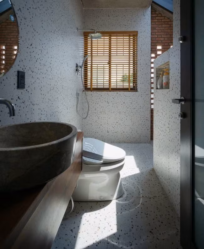 Phòng vệ sinh trông hiện đại hơn với việc sử dụng gạch terrazzo để ốp tường và lát nền (nguồn: Archdaily, ảnh: Quang Trần) Ba phòng ngủ bố trí trên cùng 1 tầng và xoay quanh khu sinh hoạt chung – nơi các thành viên gia đình có thể ngồi cạnh nhau và ngắm bầu trời đêm thông qua ô mái kính. Tổng diện tích mỗi sàn chỉ vỏn vẹn trong 80 m2.