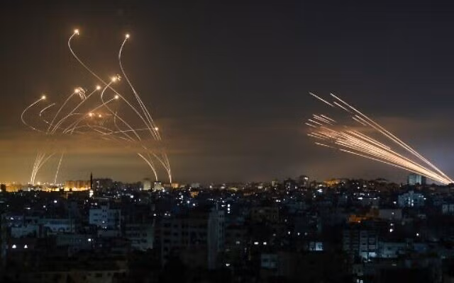 Rocket (bìa phải) được nhìn thấy trên bầu trời đêm, được bắn về phía lãnh thổ Israel từ Beit Lahia ở phía bắc Dải Gaza vào ngày 14/5/2021, trong khi các tên lửa đánh chặn Iron Dome bay lên để đánh chặn chúng.