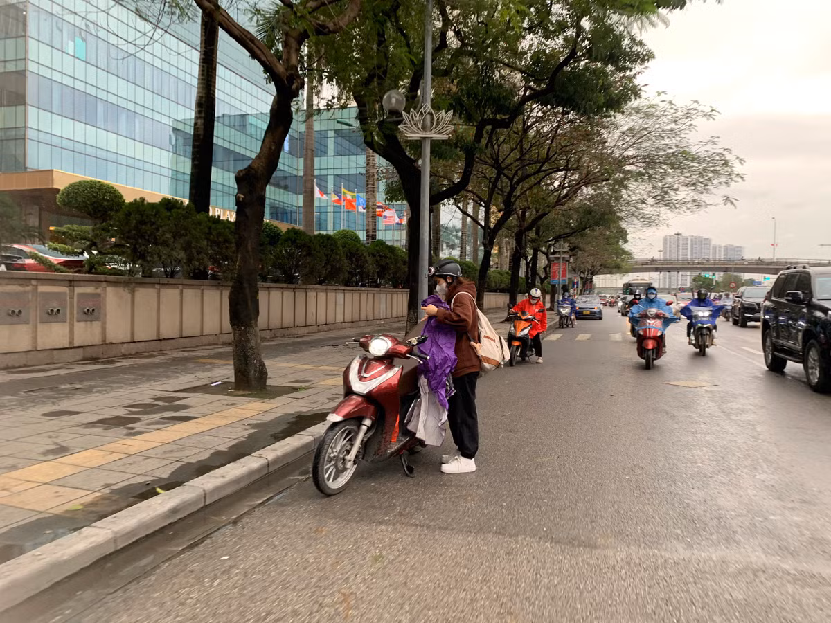 Nhiều người đi xe máy buộc phải dừng lại để mặc áo mưa.