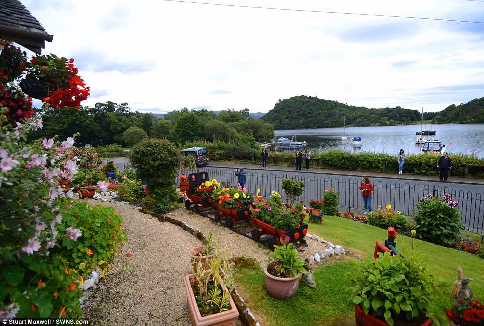 Một nhóm du khách chụp ảnh bên ngoài khu vườn bên bờ hồ Loch Lomond.
