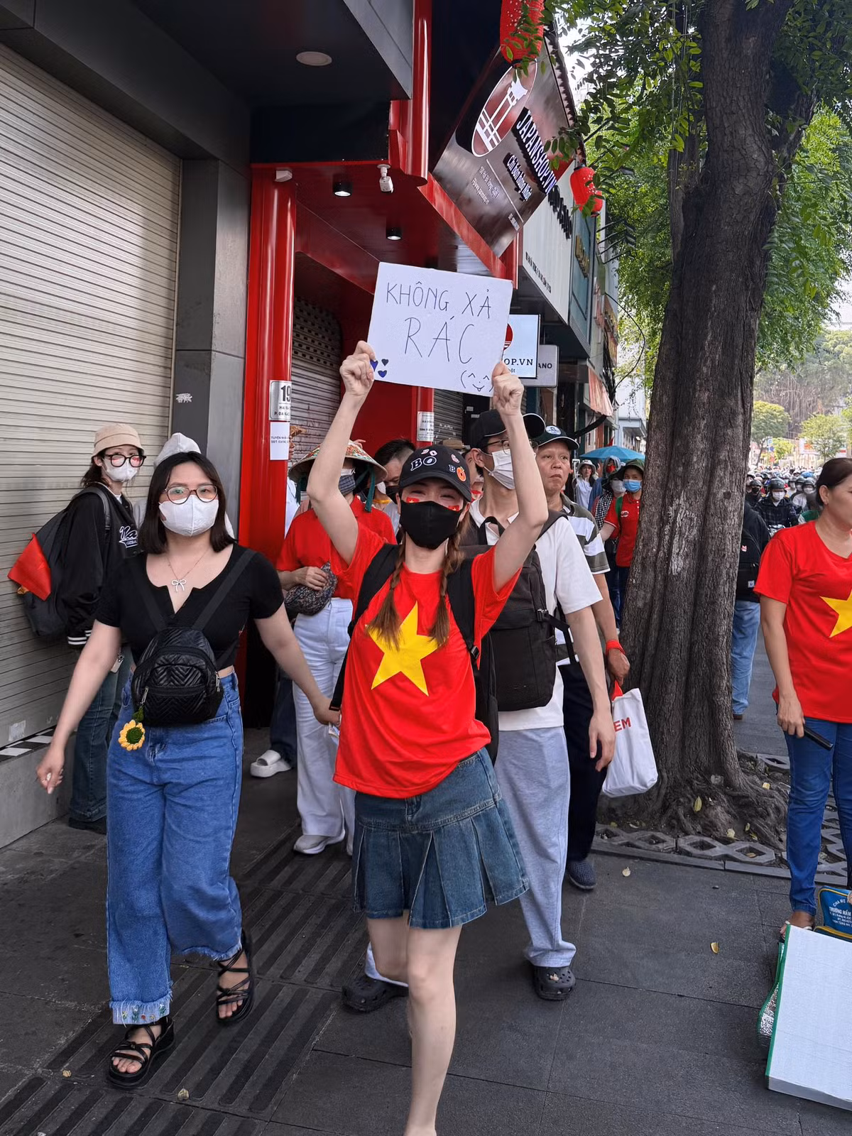 Ca sĩ Hòa Minzy mặc áo cờ đỏ sao vàng, cầm biển "Không xả rác" khi đến xem tổng duyệt. Ảnh: FB Hòa Minzy
