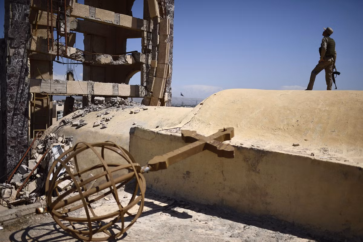 Một dân quân đứng gác trên nóc nhà thờ Thánh John ở thị trấn Qaraqosh, cách thành phố Mosul khoảng 30 km, ngày 16/4/2017. Một số gia đình đã quay trở về thị trấn này sau thời gian “chạy loạn”. Ảnh: The Atlantic.