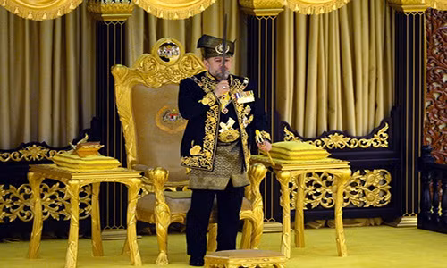 Sultan Muhammad V hôn lên thanh bảo kiếm. Ông đeo dây đai thêu hoa văn bằng ren vàng và mang các vật trang trí của hoàng gia làm bằng vàng, ngọc bích và ngà voi. Ảnh: Bernama.