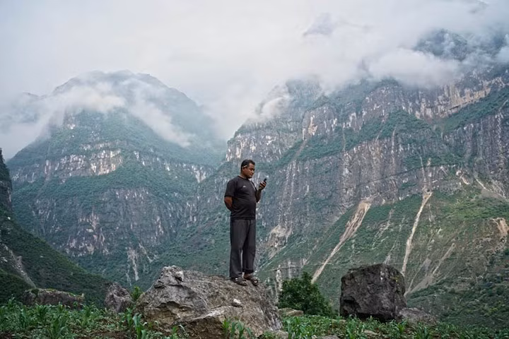 Một dân làng đứng trên mỏm đá để nhận tín hiệu điện thoại di động. Ngôi làng giữa núi này từng là một nơi yên bình và khá giả nhờ đất đai màu mỡ, không bị ảnh hưởng từ chiến tranh và cướp bóc. Nhưng bây giờ đã khác, nó bị cô lập và hầu hết người dân sống trong nghèo đói.