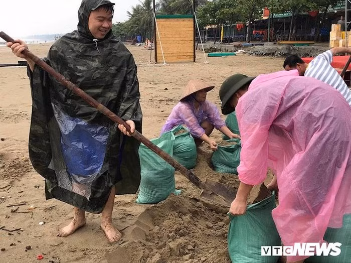 Người dân khẩn trương lấy cát để chặn mái tôn, tường rào, bảo vệ nhà cửa, hàng quán trước bão số 3.