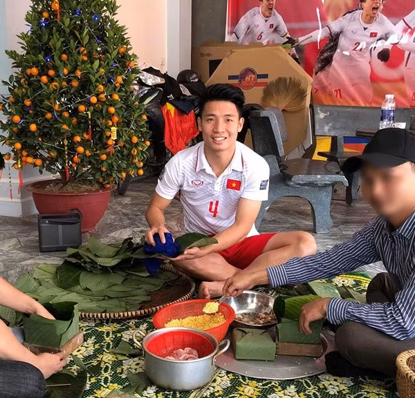 Trung vệ Bùi Tiến Dũng về nhà vẫn mặc quần đùi áo số ngồi gói bánh cùng gia đình.