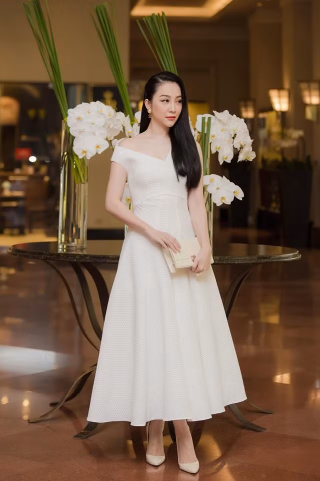 Kiểu đầm trắng lệch vai nữ tính được Linh Nga phối với giày trắng và túi xách trắng cực kỳ tinh tế và sang chảnh.