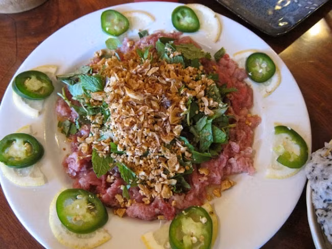 6. Món thịt bò tái chanh (Việt Nam): Món ăn này sử dụng thịt bò tươi, thái lát mỏng và ướp với nước cốt chanh để làm thành món thịt bò chín tái với axit từ chanh. Người Việt Nam ăn món này với ớt, hành khô và đậu phộng rang và một số rau thơm.