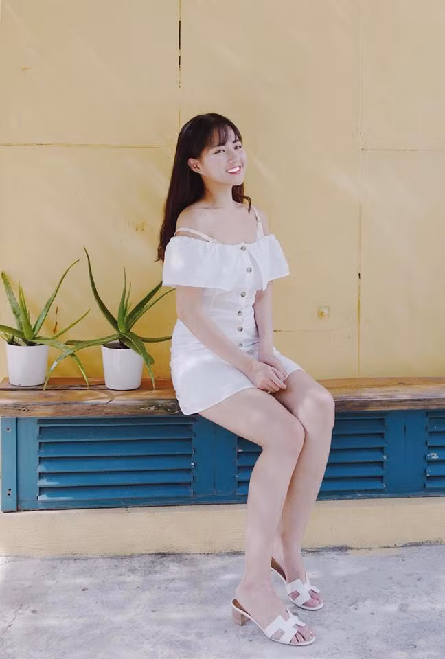 Chiếc váy trễ vai được cô kết hợp với đôi đép trắng cùng tông nữ tính.