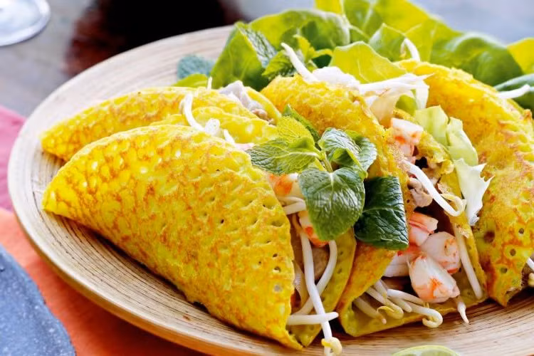 Bánh xèo là những chiếc bánh nóng hổi ngon, giòn với thịt lợn, tôm và giá đỗ, cùng một số loại rau thơm. Để thưởng thức món ăn này như người địa phương, hãy cắt nó thành những miếng nhỏ, cuộn trong bánh tráng hoặc lá rau diếp và nhúng nó vào một loại nước sốt đặc biệt.