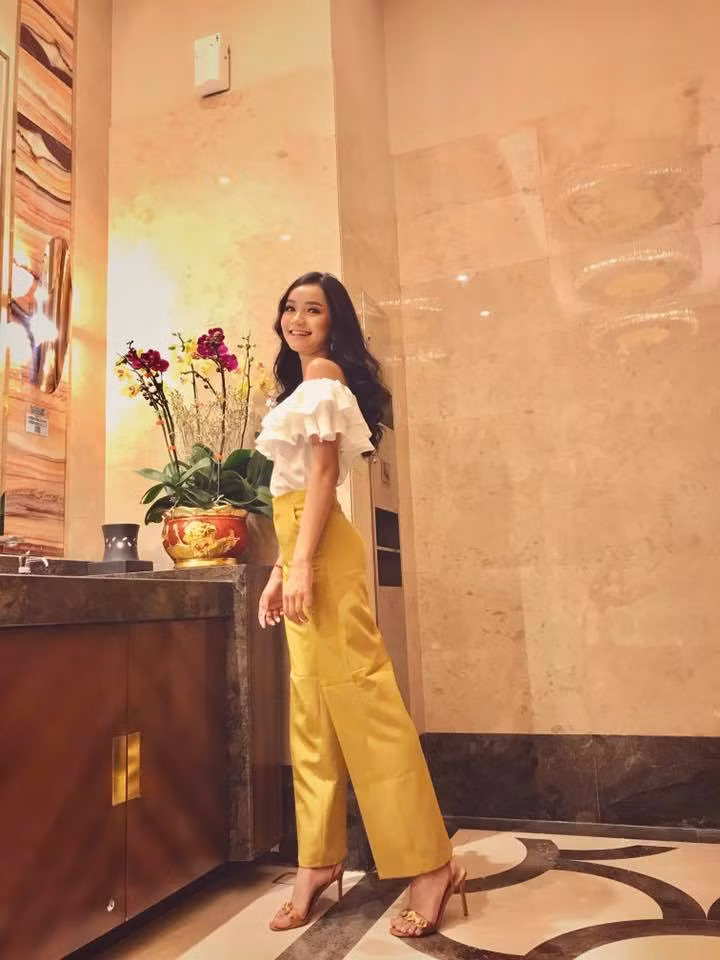 Cô nàng kết hợp áo sơ mi trễ vai với quần vàng sang chảnh.