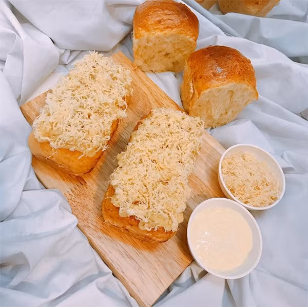 Thoạt nhìn bề ngoài thì món bánh phô mai mới lạ này cũng đều giống như những loại bánh mì gối bình thường có phủ ruốc bông phía trên. Nhưng sự thực thì còn rất nhiều điều đặc biệt phía sau nếu như không thưởng thức thì bạn không thể nào cảm nhận hết được. Ảnh: New24h. 
