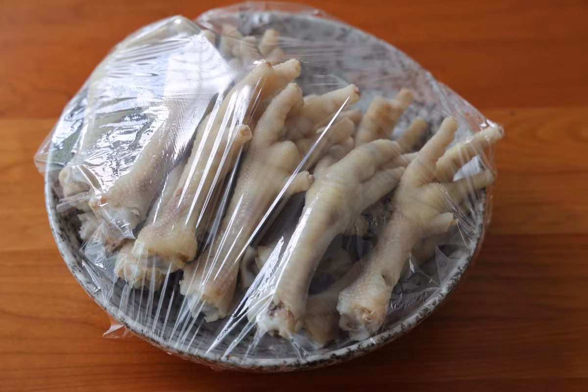 Tiếp đó vớt chân gà ra ngoài, để cho ráo nước rồi bỏ vào đĩa, bọc kín, cho lên ngăn đá khoảng 20 phút.