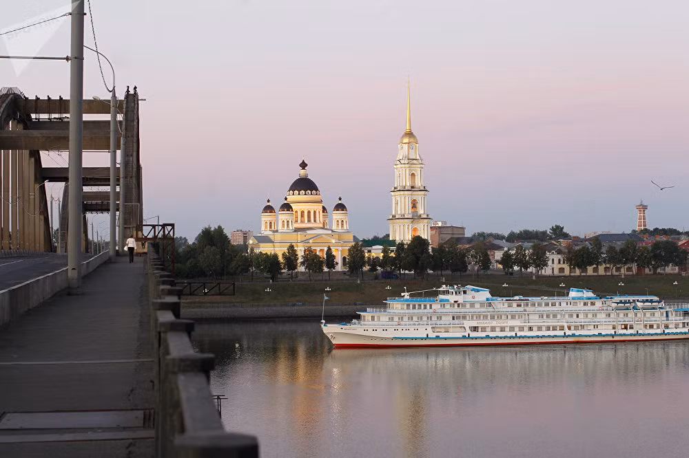 Thuyền du lịch thong thả di chuyển trên dòng sông Volga. Thánh đường Transfiguration ở phía sau.