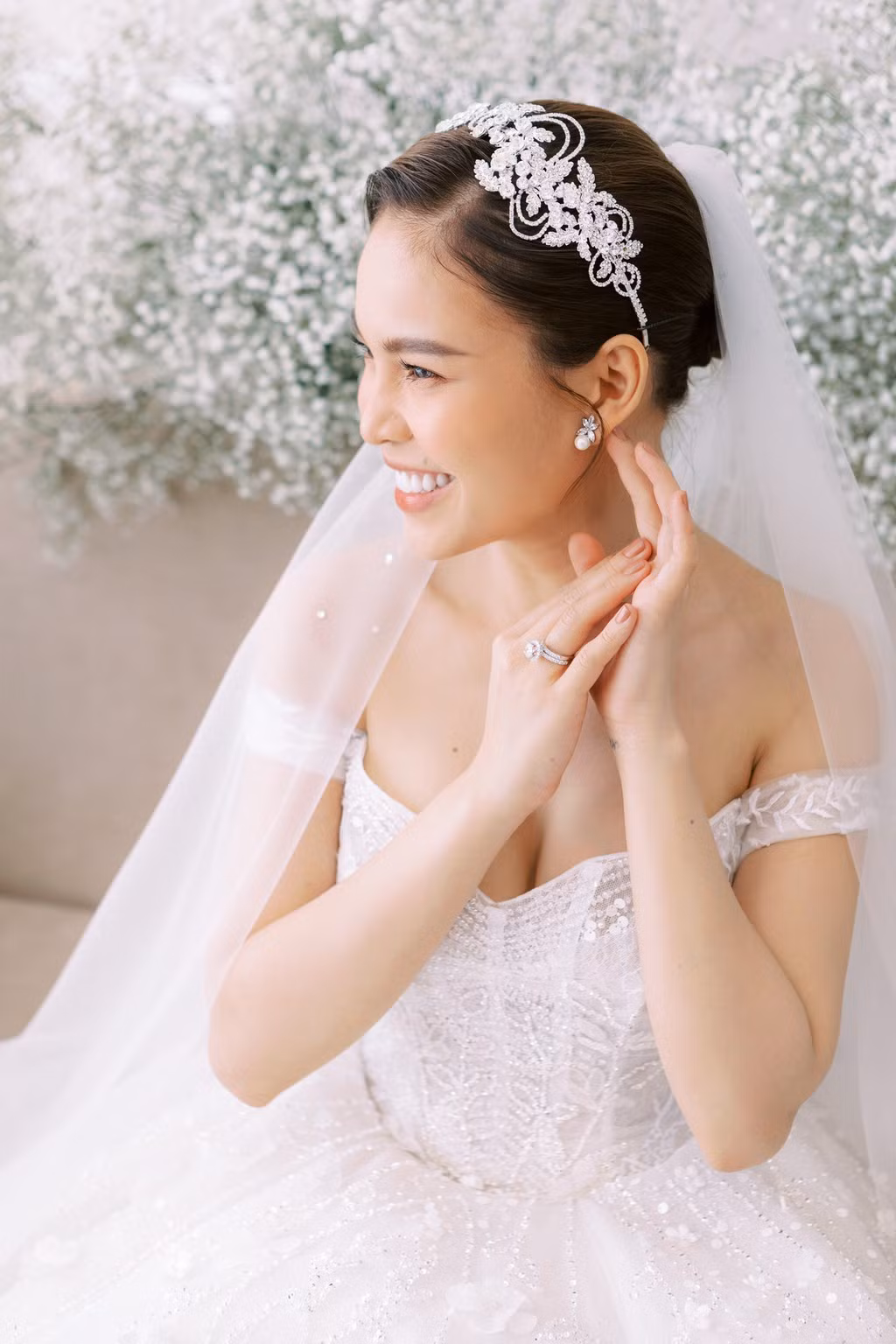 Nữ ca sĩ sinh năm 1989 toát lên vẻ rạng ngời trong thiết kế cưới màu trắng trễ vai, khoe khéo vòng một gợi cảm và bờ vai quyến rũ.