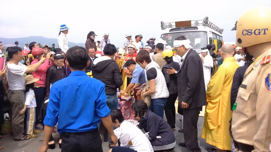 Đại diện Ban tổ chức lễ tang và người nhà đang chuẩn bị làm lễ cúng trong lúc xe dừng chân nghỉ ngơi theo phong tục địa phương.