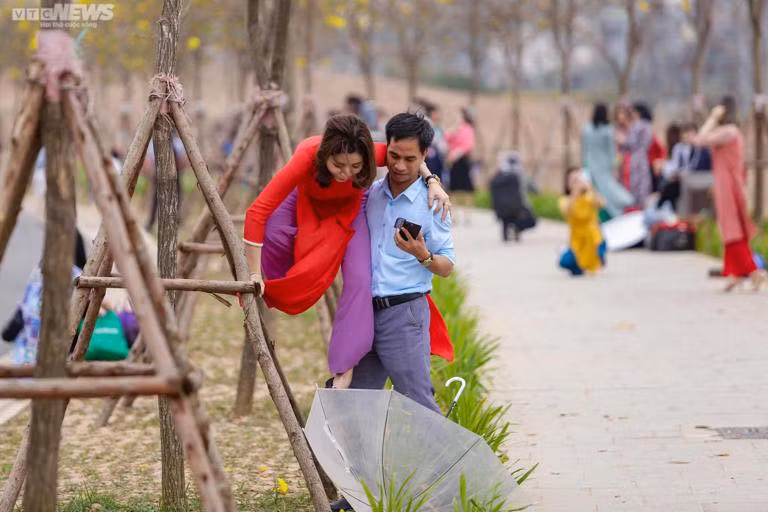 Ngay cả các anh chồng cũng cực kỳ chiều vợ, sẵn sàng đỡ vợ trèo lên cây để có được bức ảnh gần với hoa phong linh nhất. Ảnh: VTC news
