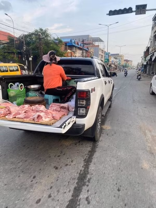 Người phụ nữ bán thịt đi nguyên chiếc xe bán tải, phần đuôi xe được cô tận dụng toàn bộ bày luôn sản phẩm.