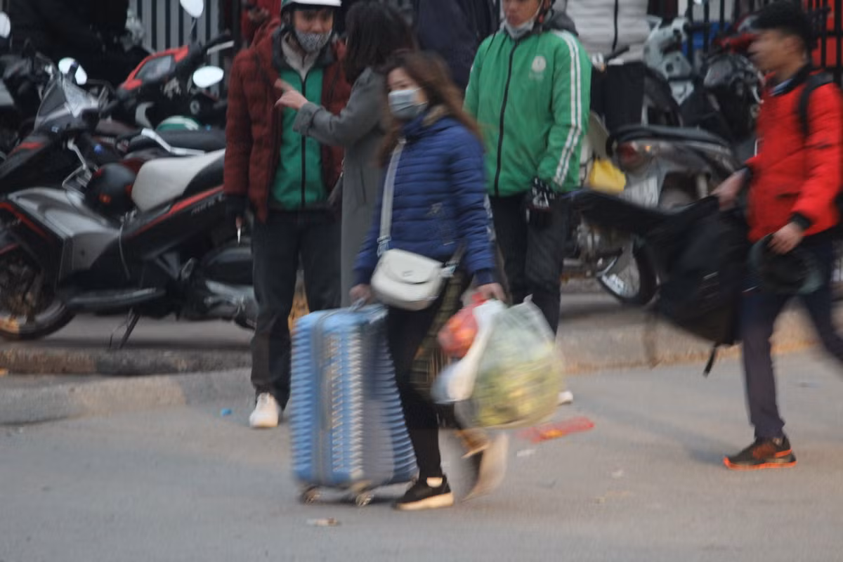 Một cô gái tỏ ra mệt mỏi khi một tay đẩy va li, tay còn lại xách nhiều túi đồ.