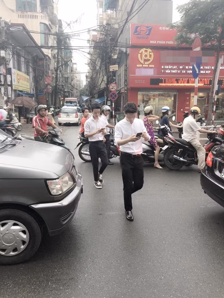 Họ mỗi người cầm trên tay một chiếc điện thoại và luôn tập trung nhìn vào màn hình không rời, dường như không quan tâm đến bất kỳ điều gì xung quanh. Thậm chí hai chàng trai còn vừa băng qua đường mà không cần quan sát, vừa đi vẫn vừa nhìn vào điện thoại bất chấp thời điểm đó đường rất đông và rất dễ xảy ra tai nạn, gây nguy hiểm cho bản thân hai người và cả những người khác.