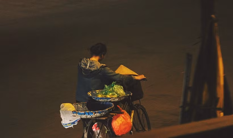 Một người phụ nữ lủi thủi dắt xe mưu sinh ở khu vực chân cầu Long Biên trong đêm vắng.