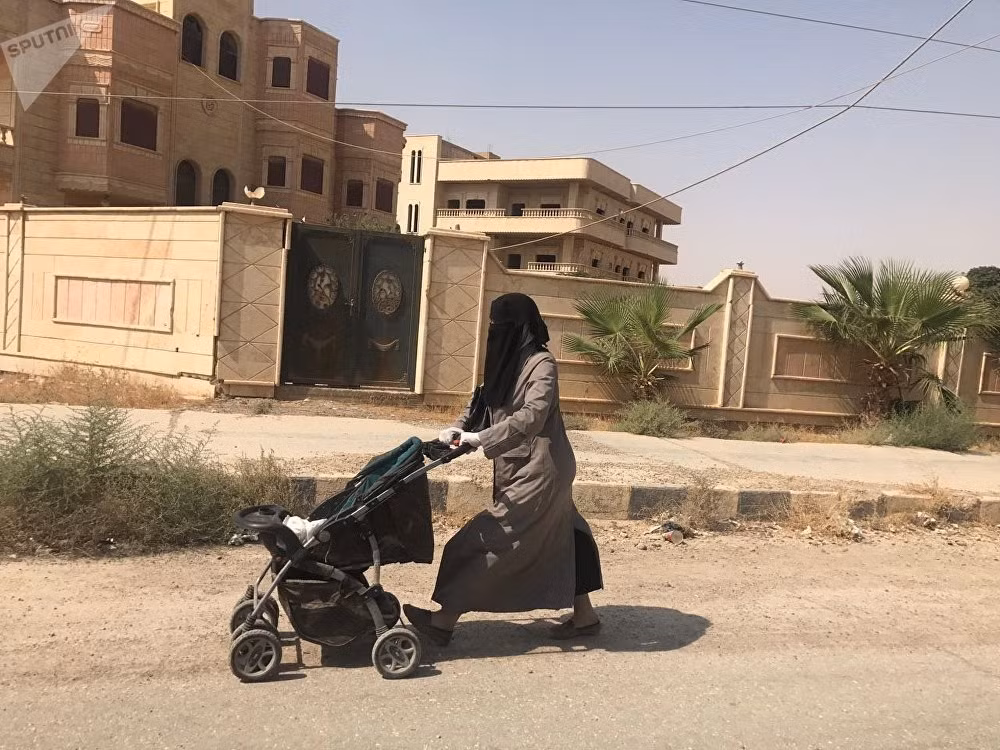Người phụ nữ đẩy chiếc xe trên đường phố Deir Ezzor. Ảnh: Sputnik.
