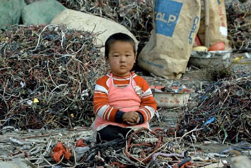 Trong thập kỷ qua, Trung Quốc đã trở thành “bãi rác” chứa thất thải điện tử từ khắp nơi trên thế giới. Ảnh: Một bé trai ngồi giữa đống rác. Ảnh: ATI.