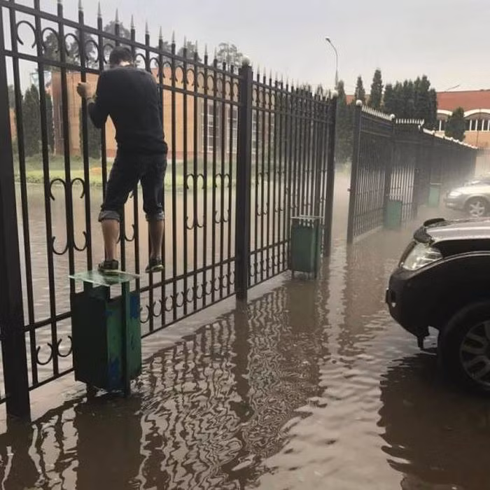 Người đàn ông phải leo lên hàng rào để đi qua khu vực ngập lụt. Ảnh: ER.