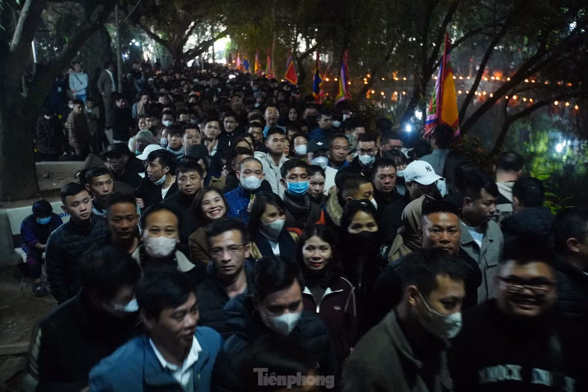 Lối vào sân đền cũng kín người. Lúc này, mưa bắt đầu đổ xuống nhưng không ngăn được sự thành tâm của người dân hướng về Đức Thánh Trần.
