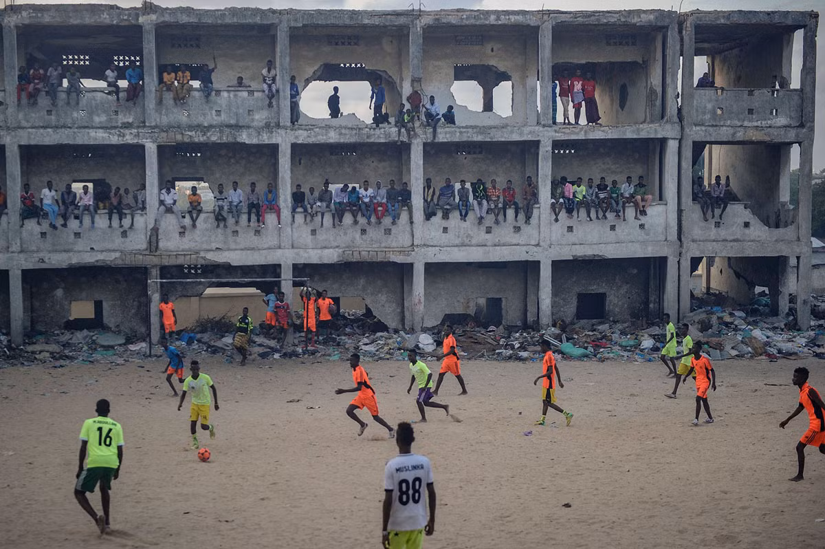 Người dân Somali đá bóng trong một ngôi trường học bị bỏ hoang sau khi nó bị bom đạn tàn phá ở Mogadishu, Somalia. Chiến tranh có thể tàn phá mọi thứ nhưng không thể ngăn được người dân Somali tìm đến môn thể thao vua. Nguồn ảnh: TA.