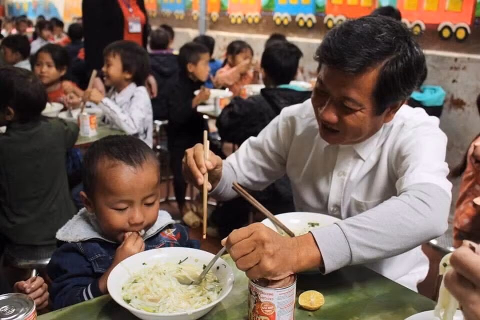 Ông Đoàn Ngọc Hải trìu mến bón phở cho một học sinh.