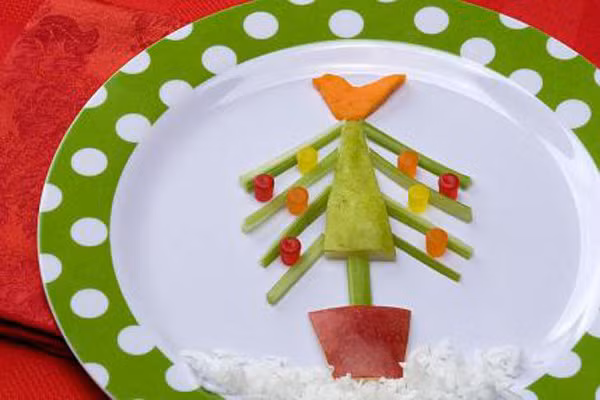 Salad ngày Giáng sinh. Món này cực kỳ dễ làm, chỉ cần một chút khéo léo của mẹ đã có ngay một cây thông noel đẹp mắt cho bé. Thân và lá cây là dưa chuột, thêm hình chóp bằng cà rốt, chậu cây bằng một lát táo đỏ, đèn nhấp nháy là những viên kẹo dẻo, bông tuyết là mayonaise. Vậy là bé đã vô tình nạp rau quả một cách dễ dàng.