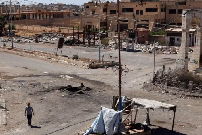 Một người đàn ông đi ngang qua hố sâu ở thị trấn Dael, tỉnh Derra, Syria sau một cuộc không kích.