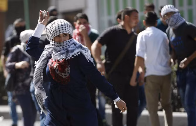 Một phụ nữ Palestine ném đá vào binh sĩ Israel ở thành phố Hebron ngày 13/10.