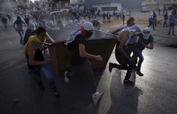 Những người biểu tình Palestine đẩy một thùng rác trong cuộc xung đột với binh sĩ Israel gần khu định cư Do thái Bet El ngày 13/10.