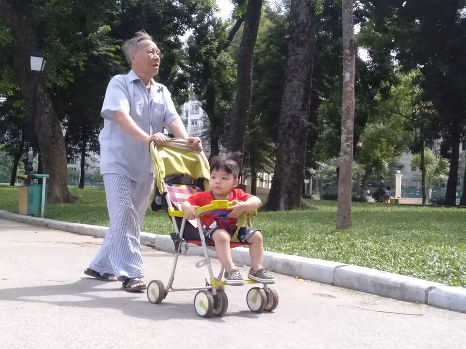 Một em nhỏ được ông đưa đi dạo quanh công viên Thống Nhất.