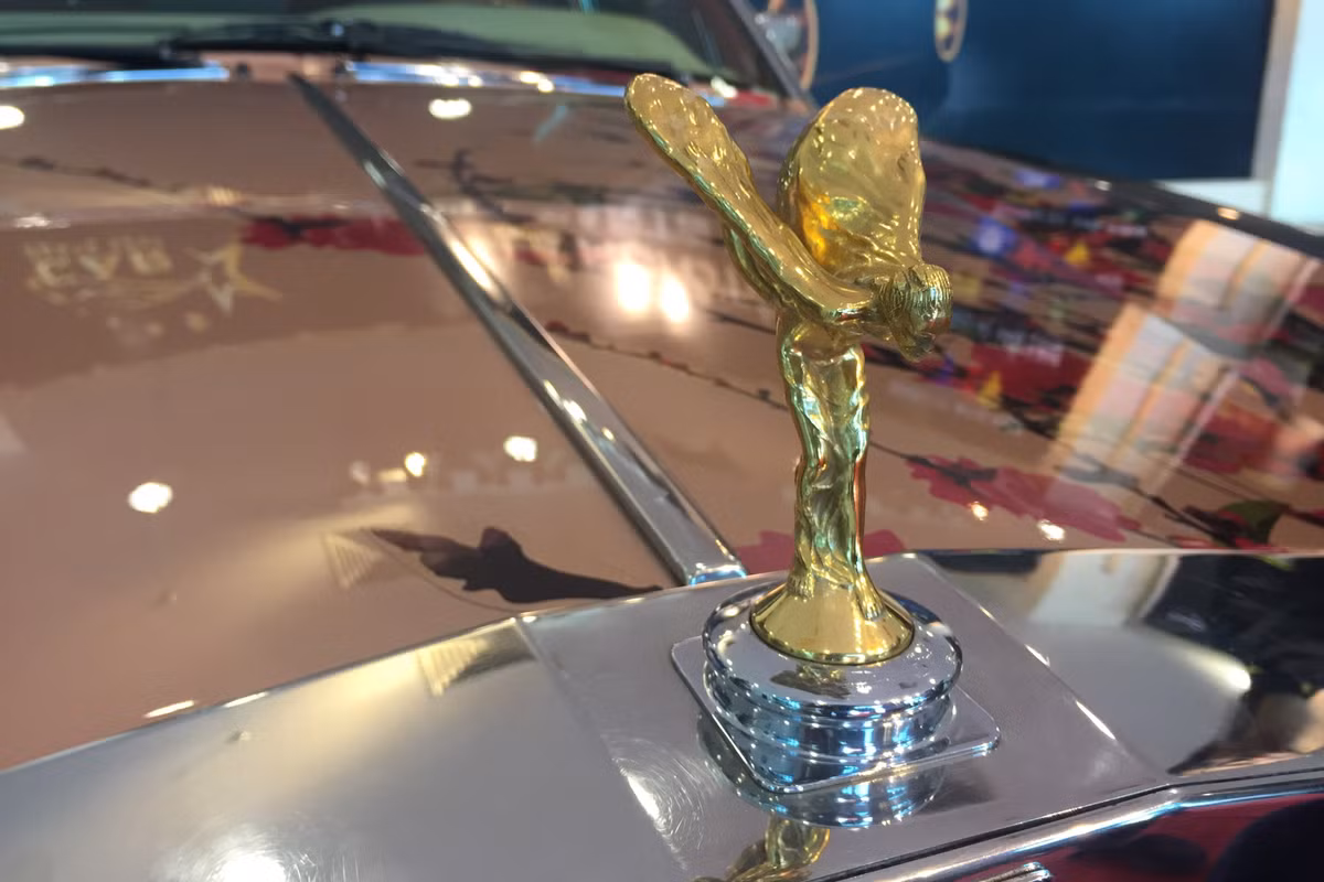 Điểm ấn tượng và đắt giá nhất chính là biểu tượng Spirit of Ecstasy đặc trưng của thương hiệu Rolls-Royce được mạ vàng. Ở thế hệ đời mới hơn, biểu tượng “người phụ nữ bay” đặt trước mũi xe có khả năng tự ẩn vào lưới tản nhiệt nếu như có lực tác động mạnh.