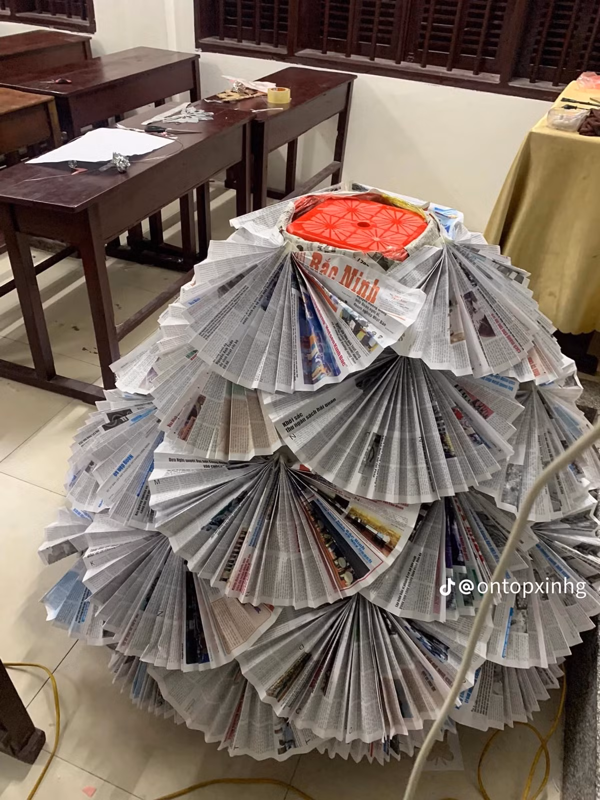 Những tờ báo được gấp lại hình chiếc quạt rồi tỉ mỉ đính lên thân váy.
