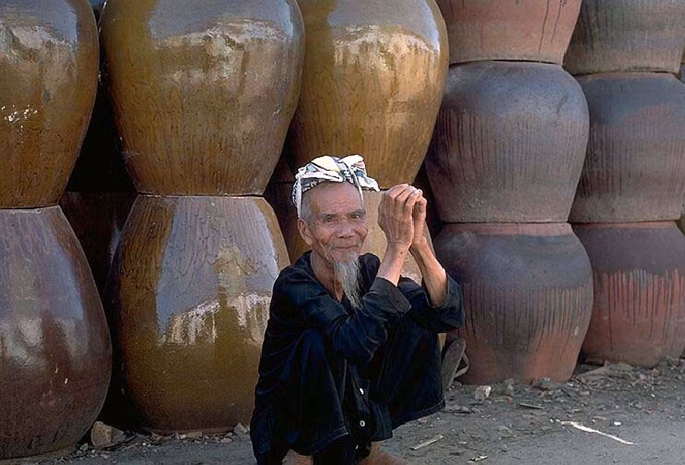 Cụ già ngồi trước những chiếc lu.