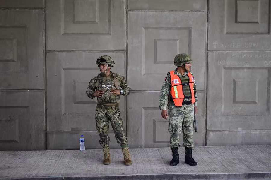 Lính thủy quân Lục chiến Mexico cùng quân cảnh của quân đội nước này đứng canh chừng những người nhập cư không có giấy tờ bên ngoài Tapachula, Chiapas, Mexico. Nguồn ảnh: Theatlantic.