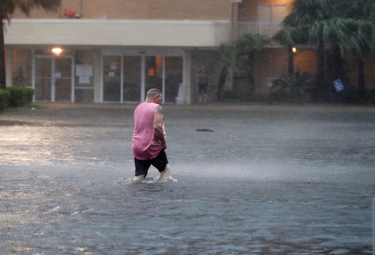 Người đàn ông lội qua bãi đỗ xe bị ngập ở Gulf Shores, Alabama, hôm 15/9.